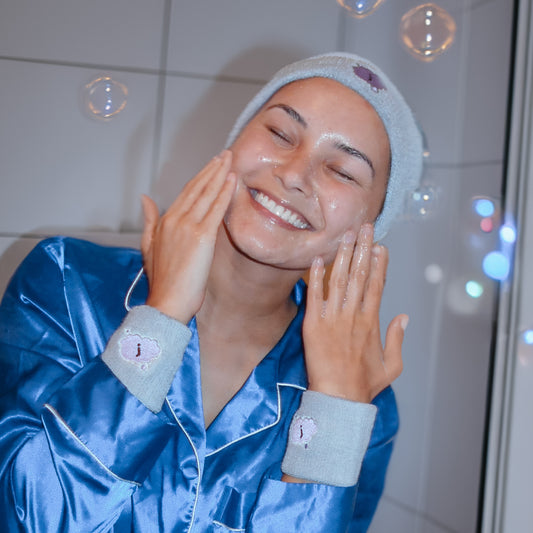 girl washing face wearing gray jellee bands with bubbles in the background